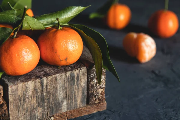 Boîte avec de savoureuses mandarines juteuses dans une boîte en bois sur fond sombre avec espace de copie — Photo