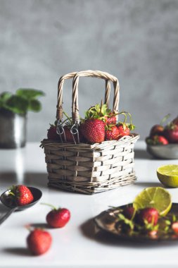 Beyaz ahşap bir masada sepetteki taze çilekler.
