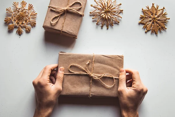 Man hands give wrapped christmas holiday handmade present in paper with red ribbon. Present box