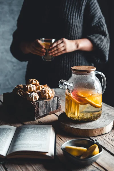 Kobieta czyta i gorąca herbata ze świeżymi grejpfrutami na drewnianej tabletce. Zdrowy drink — Zdjęcie stockowe