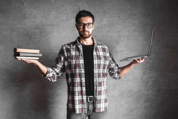 Muž držet v ruce knihu s notebookem na šedém pozadí zdi. Royalty Free Stock Fotografie