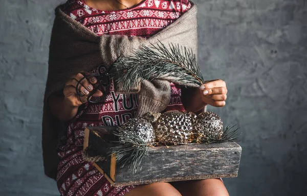 Mädchen im Weihnachtskleid hält Kugeln in einer Holzkiste, Urlaub — Stockfoto