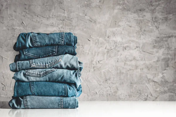 Stack av blå jeans på en grå bakgrund Royaltyfria Stockfoton