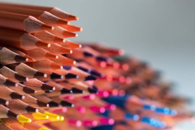 Gri arka planda bir sıra gökkuşağında renkli tahta kalemler çiziyor. Çizim, hobi, meslek