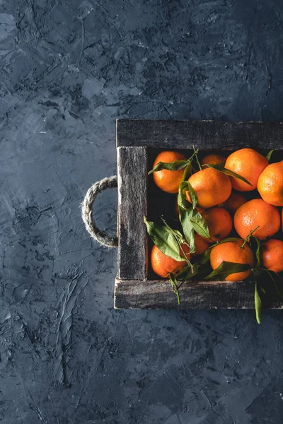 Caixa com saborosas tangerinas suculentas em caixa de madeira no fundo escuro com espaço de cópia — Fotografia de Stock