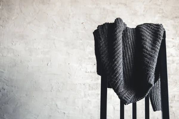 Šedý svetr pletený na zadní straně dřevěné židle Stock Fotografie
