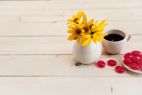 Un bel arrangement de fleurs jaunes, des bonbons et une tasse de café — Photo