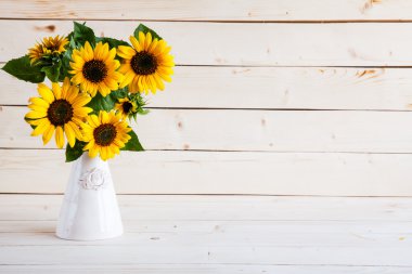 eski ahşap bir masa üzerinde bir vazoda sonbahar ayçiçeği bir buket.