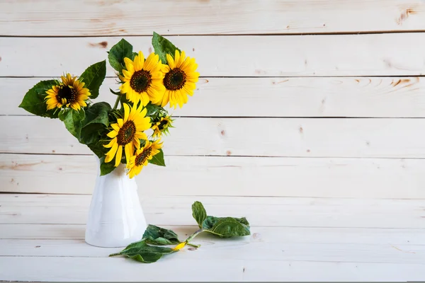 A bouquet of autumn sunflowers in a vase on a grungy wooden table. — Stock Photo, Image