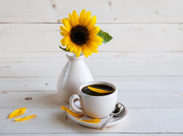 Girasole e una tazza di caffè su uno sfondo di legno — Foto Stock