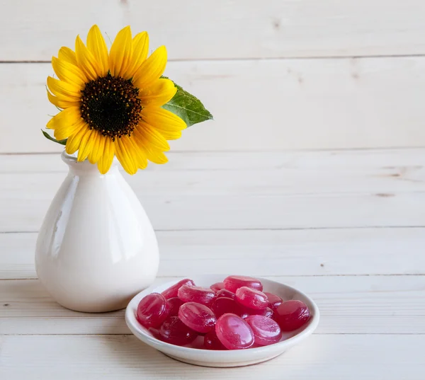 Sonnenblume auf Holzgrund mit roten Bonbons — Stockfoto