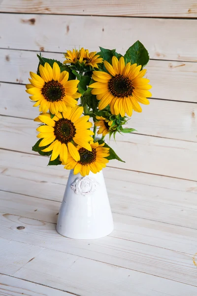 A bouquet of autumn sunflowers in a vase on a grungy wooden table. — Stock Photo, Image