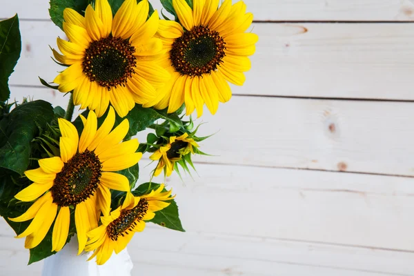 A bouquet of autumn sunflowers in a vase on a grungy wooden table. — Stock Photo, Image