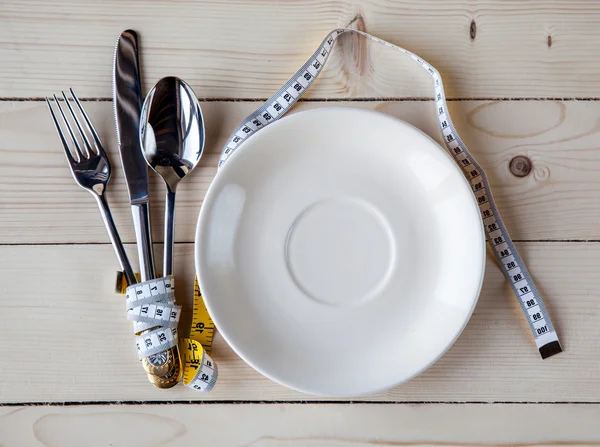 Plaque vide avec ruban à mesurer, couteau et fourchette. Alimentation diététique sur table en bois — Photo