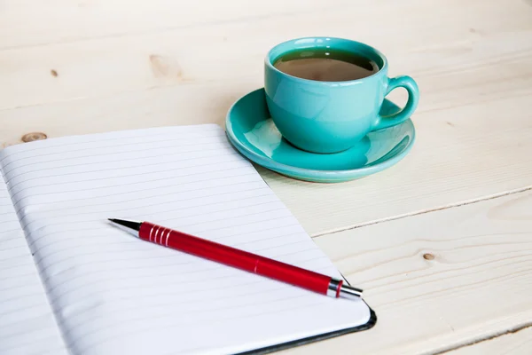 Ouvrez un carnet blanc vierge, un stylo et une tasse de thé sur le bureau — Photo