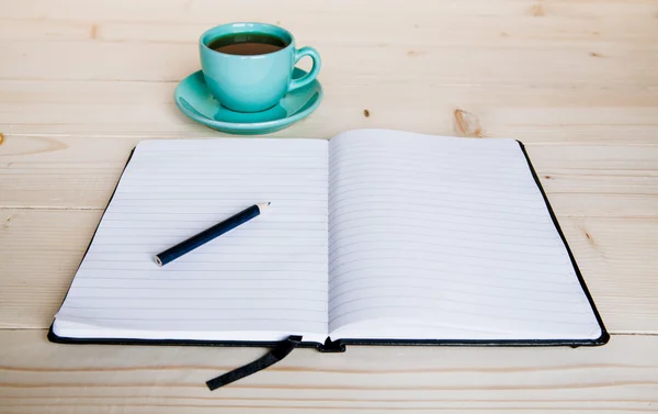 Ouvrez un carnet blanc vierge, un stylo et une tasse de thé sur le bureau — Photo