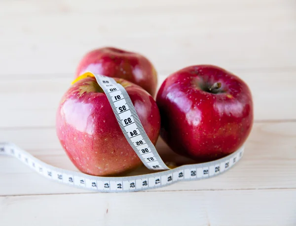 Pommes mesurées le mètre sur un fond en bois — Photo