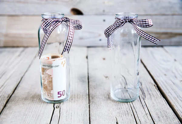 Geld in einem Glas und einem leeren Glas — Stockfoto