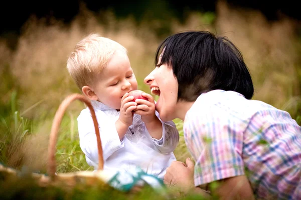 Mom and son eating fruit with wicker baskets — Stock Photo, Image