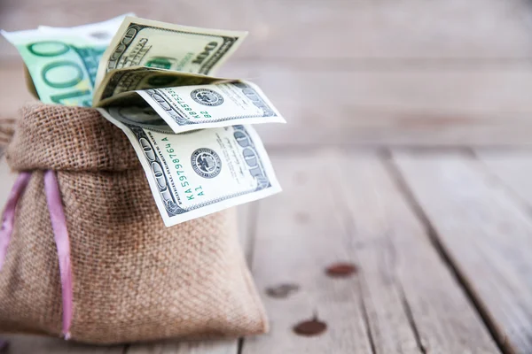 Dinero en cilicio y monedas esparcidas sobre un fondo de madera —  Fotos de Stock