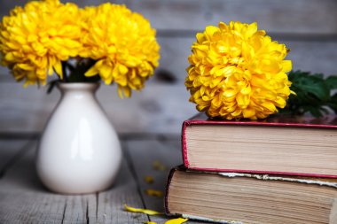 Çiçekler. Güzel sarı Kasımpatı vintage bir vazo içinde. Bir fincan kahve. Parlak Servais, kupa ve uçan daire... Güzel kahvaltı. Ahşap arka plan üzerinde eski kitaplar.