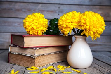 Çiçekler. Güzel sarı Kasımpatı vintage bir vazo içinde. Bir fincan kahve. Parlak Servais, kupa ve uçan daire... Güzel kahvaltı. Ahşap arka plan üzerinde eski kitaplar.