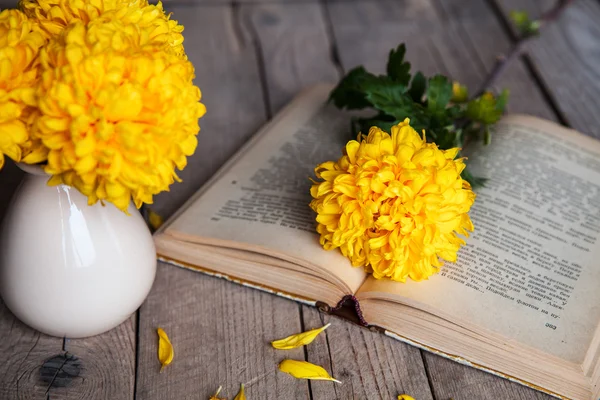 Flores. Belo crisântemo amarelo em um vaso vintage. Uma xícara de café. Servos brilhantes, xícara e pires.. Belo pequeno-almoço.Livros antigos em um fundo de madeira . — Fotografia de Stock