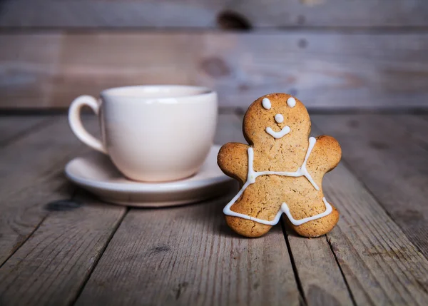 Christmas homemade gingerbread man on wooden background. Large cup of coffee — Stock Photo, Image
