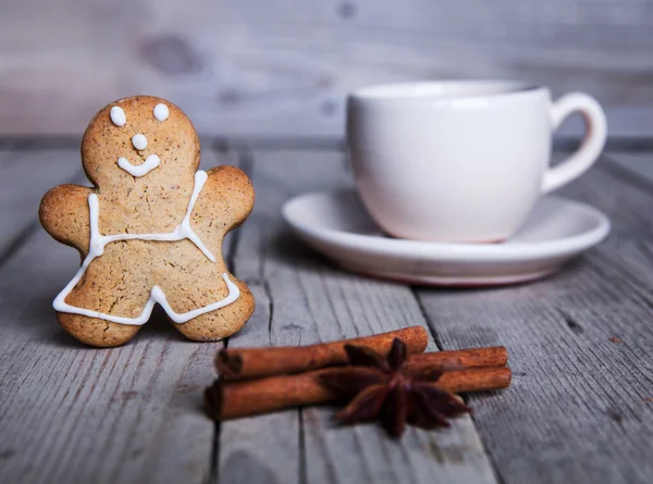 Christmas homemade gingerbread man on wooden background. Large cup of coffee — Stock Photo, Image