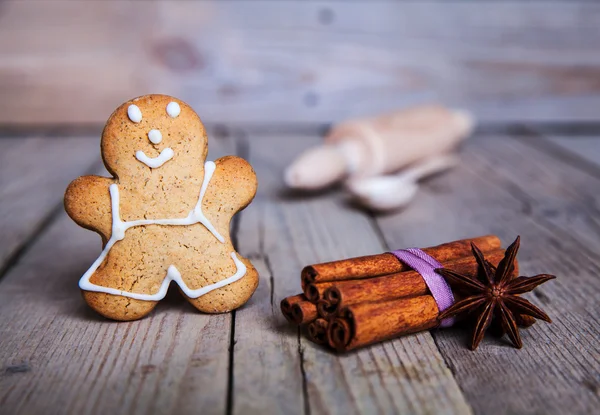 Rolling pin and homemade gingerbread men biscuits on a wooden board with flour — Stock Photo, Image