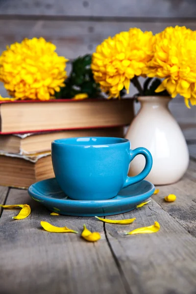 Fiori. Bellissimo crisantemo giallo in un vaso vintage. Una tazza di caffè. Servais luminoso, tazza e piattino.. Bella colazione. Vecchi libri su uno sfondo di legno . — Foto Stock