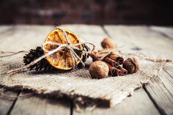 Naranja seca atada con piñas y nueces sobre un fondo de madera — Foto de Stock