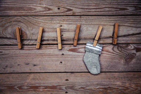Γκρι κάλτσα με ένα μανταλάκι πάνω σε ξύλινα φόντο — Φωτογραφία Αρχείου