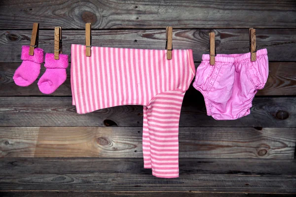 Dětské oblečení na prádelní šňůru, na dřevěné pozadí — Stock fotografie