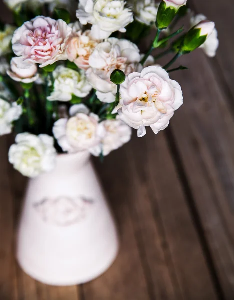 Delicate bouquet of carnations in a vase on a vintage wooden bac — Stock Photo, Image