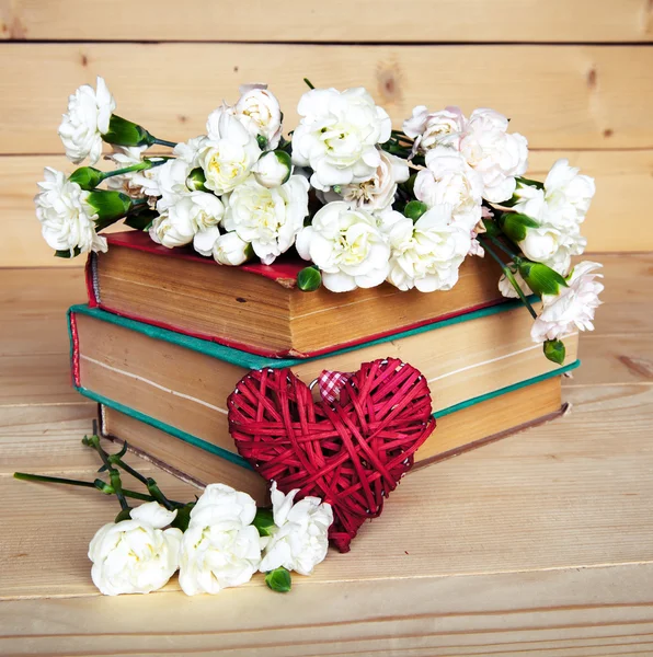Gentle carnation in the old book on a wooden background. Valenti — Stock Photo, Image
