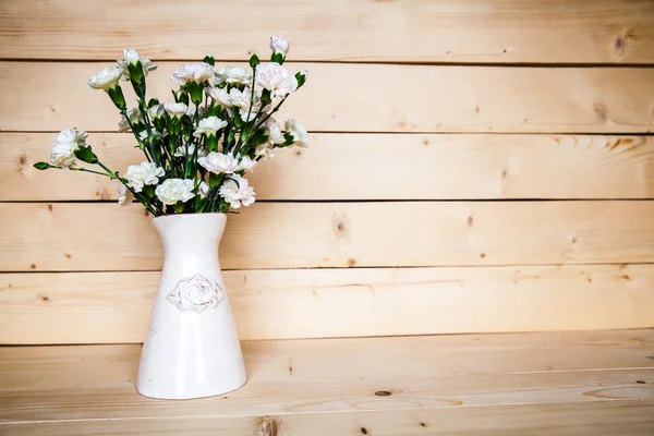 Delicate bouquet of carnations in a vase on vintage wooden background — Stock Photo, Image