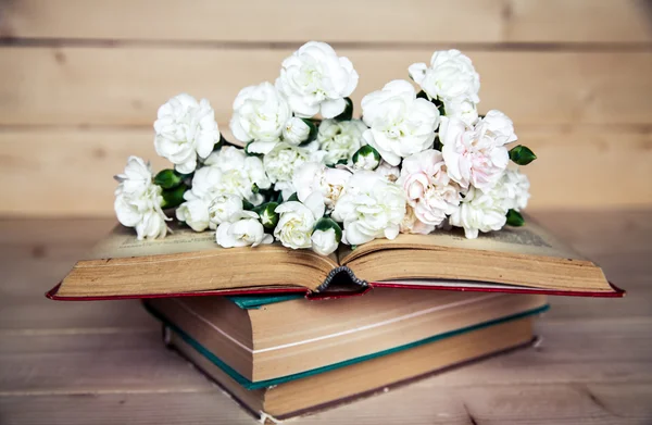 Gentle carnation in the old book on a wooden background — Stock Photo, Image