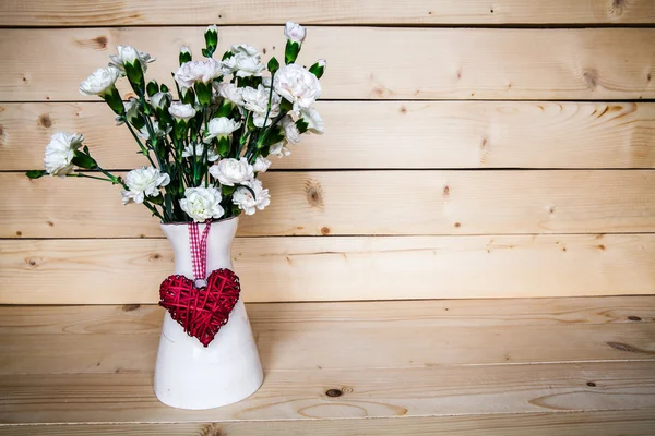 Zartes Bouquet von Nelken in Vase mit Herz auf Holzgrund. Valentinstag — Stockfoto