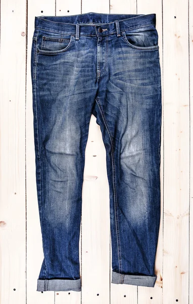 Голубые джинсы брюки изолированы на деревянном фоне — стоковое фото