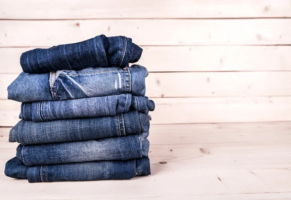 Modische Kleidung. Haufen Jeans auf einem hölzernen Hintergrund — Stockfoto