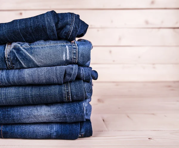 Modische Kleidung. Haufen Jeans auf einem hölzernen Hintergrund — Stockfoto