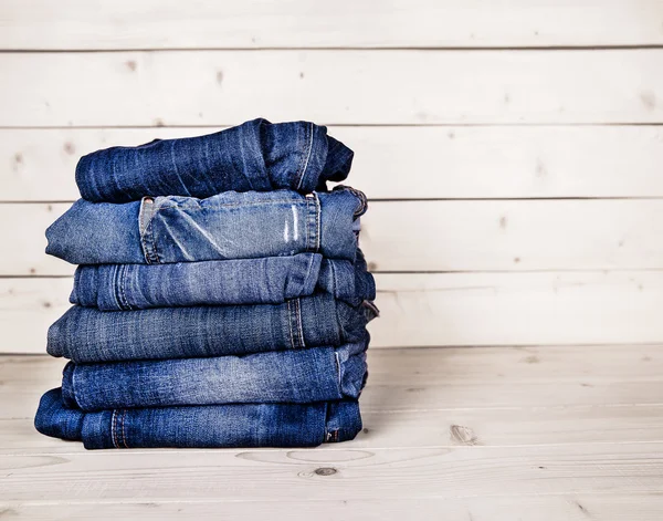 Fashionable clothes. pile of jeans on a wooden background — Stock Photo, Image