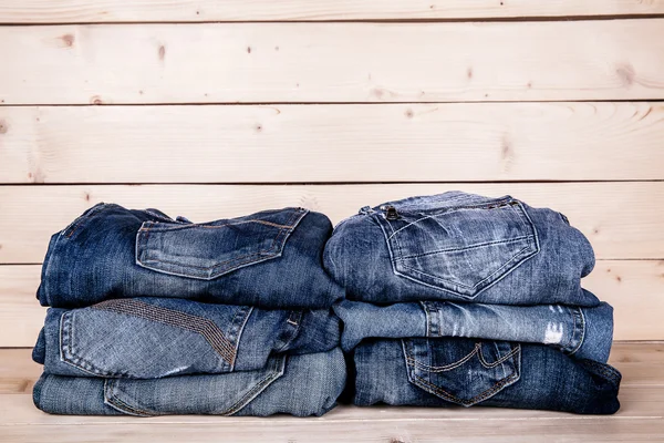 Fashionable clothes. pile of jeans on a wooden background — Stock Photo, Image