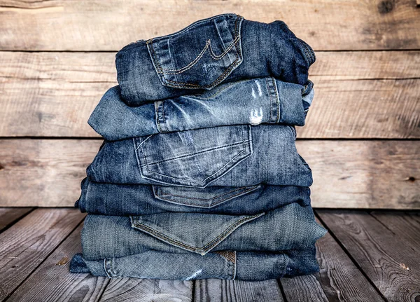 Modische Kleidung. Haufen Jeans auf einem hölzernen Hintergrund — Stockfoto