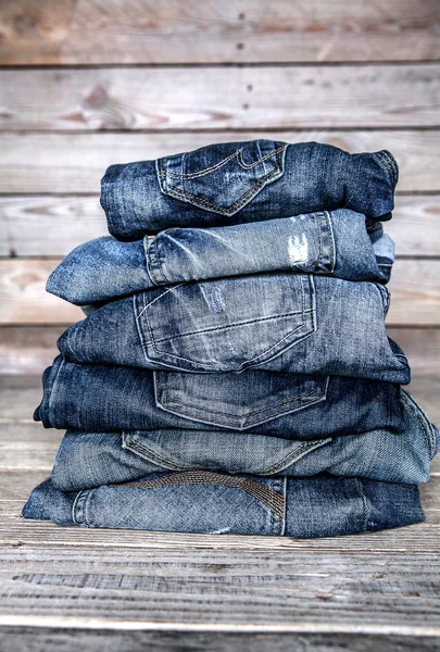 Modische Kleidung. Haufen Jeans auf einem hölzernen Hintergrund — Stockfoto