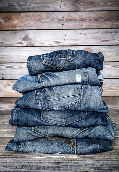 Modische Kleidung. Haufen Jeans auf einem hölzernen Hintergrund — Stockfoto