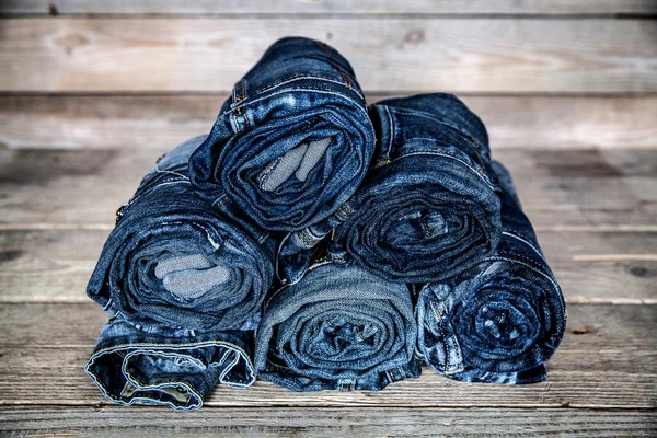 Clothing. twisted jeans on a wooden background — Stock Photo, Image