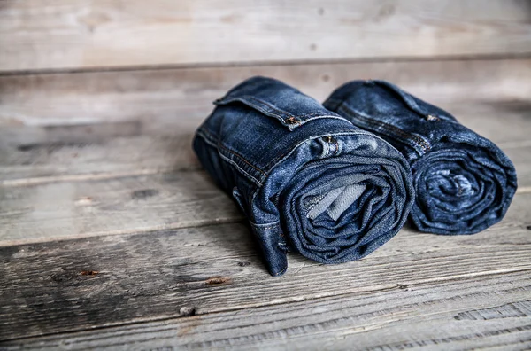 Clothing. twisted jeans on a wooden background — Stock Photo, Image