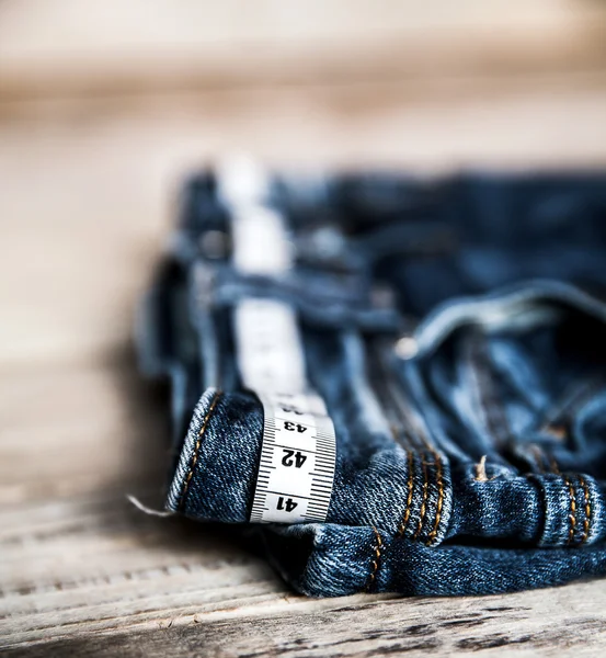 Jeans and centimeter on a wooden background. clothing — Stock Photo, Image